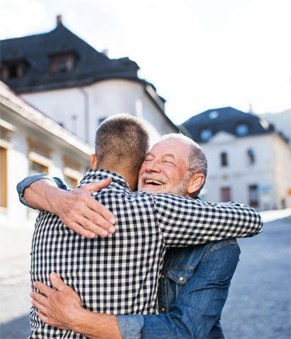 An adult hipster son and his senior father hugging